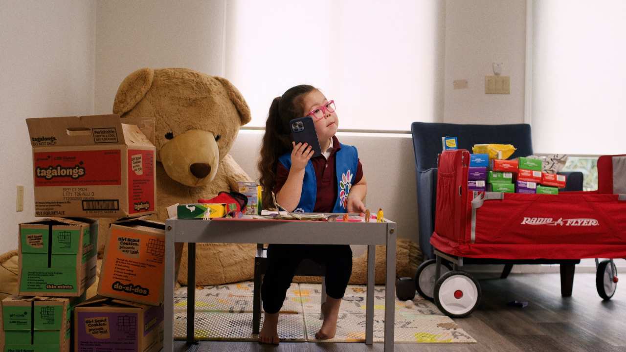 a girl at a table next to a wagon of cookies